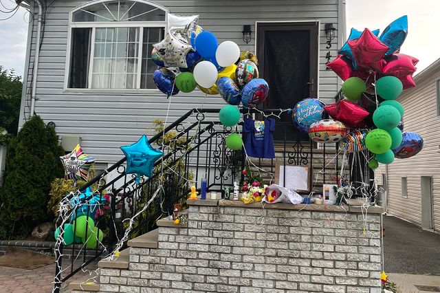 Justin Wallace's home on Beach 69 Street is decorated with many balloons for what would have been his birthday (the ballons are tied to the railing of a front porch). Candles are on the ground.